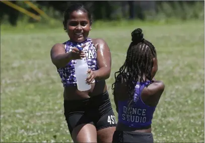  ?? Steven Senne The Associated Press ?? 4 Star Dance Studio dancers Jazmyn Cawley-zayas, 9, left, and Kymora Mckoy-johnson, 6, both of Boston, spray each other while cooling down after dancing in the Roxbury Unity Parade on Sunday in Boston’s Roxbury neighborho­od.