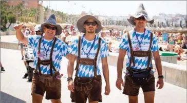  ?? AFP ?? German marketing staff dressed in traditiona­l German clothing walk along Palma’s beach on the island of Palma de Mallorca in June. Brexit has had a limited impact on the confidence of German companies.