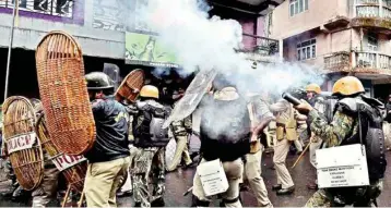  ?? (PHOTO: PTI) ?? Security personnel fire tear gas during a protest by Gorkha Janmukti Morcha (GJM) activists in Darjeeling on Saturday