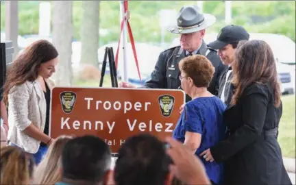  ?? ERIC BONZAR — THE MORNING JOURNAL ?? Family members of Ohio State Highway Patrol Trooper Kenneth Velez unveil a memorial highway plaque during a ceremony held in Lakewood, July 10.