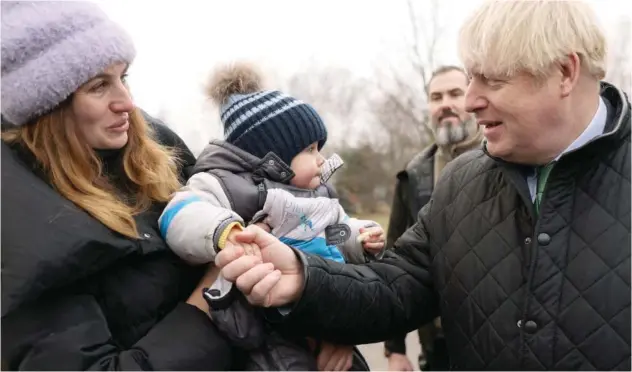  ?? Reuters ?? ↑
Boris Johnson shakes hands with a kid as his mother looks on in Bucha on Sunday.