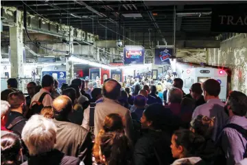  ??  ?? Commuters try to get a train as they wait for service to be restored after a severe thundersto­rm downed trees that caused power outages resulting in several Metro-North lines being suspended at Grand Central Terminal in New York City. — AFP photo