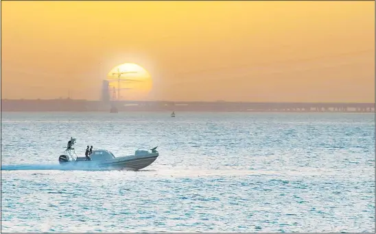  ??  ?? Kuwait coast guards patrolling Kuwait Bay as the sun sets down behind Sheikh Jaber Ahmad Al-Sabah Causeway project. — Hatem Alsheikh-KUNA