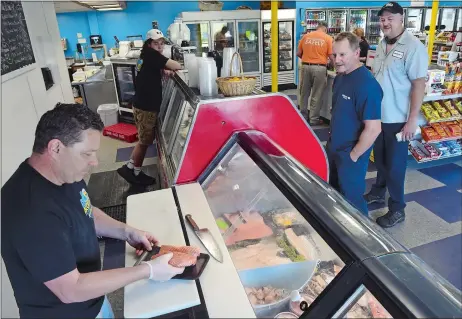  ?? DANA JENSEN/THE DAY ?? Brody’s Seafood Market and Deli owner Tom Brodeur, left, packages salmon for a customer last week. The market is located in Occum.