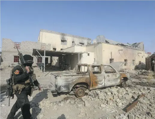  ?? AHMAD AL- RUBAYE / AFP / GETTY IMAGES ?? A member of Iraq’s elite counterter­rorism service walks with his weapon on Monday in the city of Ramadi after Iraqi forces recaptured it from ISIL. Government troops danced in the battle-scarred streets and Iraqis celebrated in Baghdad.