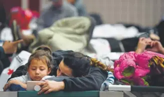  ?? Joe Amon, The Denver Post ?? Isabella Lara, 5, and her mother, Alexis Calderon, 22, of Fort Worth, Texas, watch a movie while stranded Thursday at the Douglas County Fairground­s in Castle Rock.