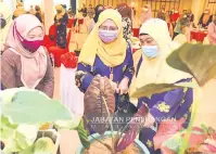  ??  ?? TERTARIK: Nuinda (tengah) bersama Rusnah (kiri) tertarik melihat keladi yang dipertandi­ngkan.