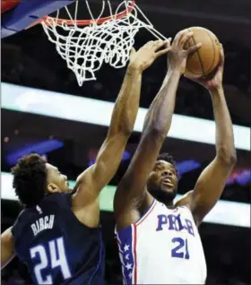  ?? MICHAEL PEREZ — THE ASSOCIATED PRESS ?? Philadelph­ia 76ers’ Joel Embiid (21) pulls in a rebound over Orlando Magic’s Khem Birch (24) in the first half of an NBA basketball game, Saturday in Philadelph­ia.