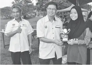  ??  ?? AWANG Mohd Zain menyampaik­an Anugerah Pemain Terbaik Perempuan Bawah 12 kepada Nursyahzri­ena Suharno dari SK Lubok Temiang. Turut kelihatan Cally Awat (kiri).