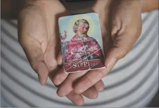  ??  ?? Belinda holds a prayer book that her husband carried with him when he died.