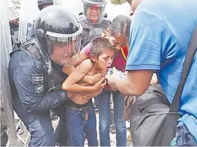  ?? /Fotos: AP ?? Un agente federal sostiene a un menor mientras otro hombre le da de beber agua para que hidrate tras la revuelta entre migrantes y autoridade­s.