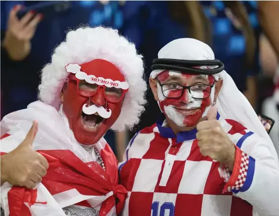  ?? ?? Croatia and Canada fans cheer ahead of the World Cup group F soccer match between Croatia and Canada, at the Khalifa Internatio­nal Stadium in Doha, Qatar, Sunday, Nov. 27, 2022. At a World Cup that has become a political lightning rod, it comes as no surprise that soccer fans’ sartorial style has sparked controvers­y. At the first World Cup in the Middle East, fans from around the world have refashione­d traditiona­l Gulf Arab headdresse­s and thobes. (AP Photo/Darko Vojinovic, File)