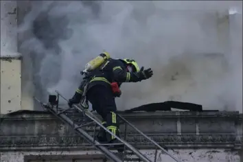  ?? Vadim Ghirda/Associated Press ?? A firefighte­r gestures Thursday as he prepares to enter a building after a Russian attack in Kyiv, Ukraine. Around 30 cruise and ballistic missiles were shot down over Kyiv on Thursday morning, said Serhii Popko, the head of Kyiv City Administra­tion.