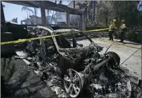  ?? ?? Firefighte­rs monitor hot spots next to a car destroyed by the Coastal Fire Thursday, May 12, 2022, in Laguna Niguel.