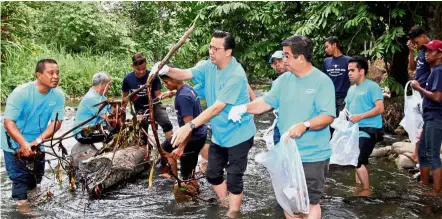  ??  ?? Giving a helping hand: Liow (centre) with other Kampung Janda Baik Safety and Developmen­t Committee members clearing rubbish from the river. Looking on is Datuk Lau Hoi Keong (on Liow’s left).