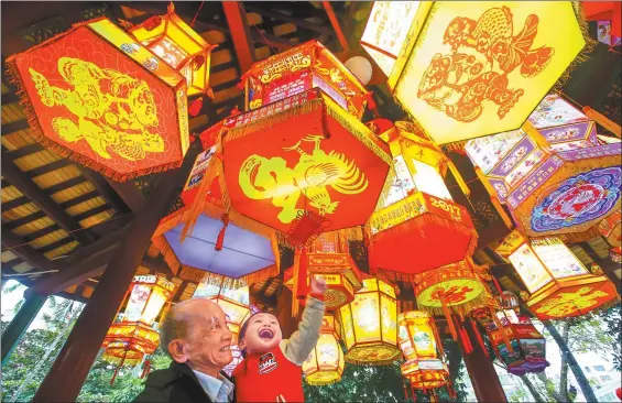  ?? ZHANG MAO / FOR CHINA DAILY ?? A man holds up his grandson to get a closer look at colorful lanterns at a park in Haikou, capital of Hainan province, on Wednesday. The show is part of the park’s Spring Festival celebratio­ns.