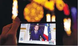  ??  ?? Macron is seen on the screen of an iPhone in Marseille, as he gives the traditiona­l New Year speech during a prime time news broadcast at the Elysee Palace on Dec 31, 2017.