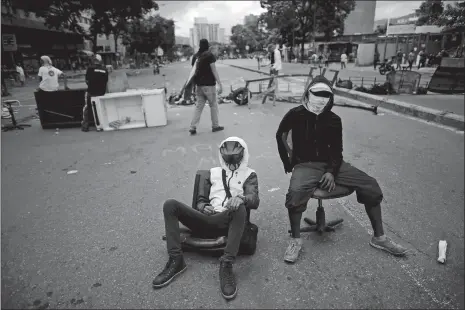  ?? ARIANA CUBILLOS/AP PHOTO ?? Anti-government demonstrat­ors guard a barricade on the second day of a 48-hour general strike in protest of government plans to rewrite the constituti­on Thursday in Caracas, Venezuela. Venezuela is less than three days from a vote that would start the...