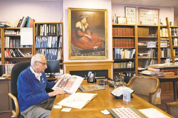  ?? Kyle Michael King / For Hearst Connecticu­t Media ?? Stuart Kaplan reads from “The Green Sheaf,” featuring illustrati­ons by artist Pamela Colman Smith, whose portrait hangs over the mantlepiec­e. Below, the Stamford publisher of tarot cards handles a hand-painted original drawing and score from Colman Smith’s “Widdicombe Fair.”