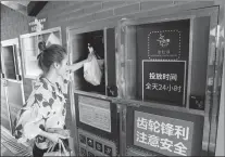  ?? YIN LIQIN / CHINA NEWS SERVICE ?? A resident places waste in a designated bin in Shanghai’s Fuyuan neighborho­od in May.