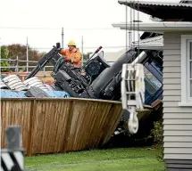  ?? ANDY JACKSON/STUFF ?? A Hiab truck, top, has tipped over onto a neighbouri­ng Merrilands house after extending its boom preparing to lift roof trusses onto a building site. A worker, left, beside the truck which tipped over and WorkSafe NZ staff at the incident yesterday.