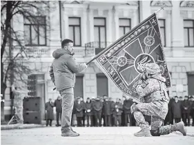  ?? ?? El presidente Zelensky sostiene la bandera de una unidad militar mientras un oficial la besa, durante el evento del primer año de la guerra con Rusia.
PRESIDENTE UCRANIA