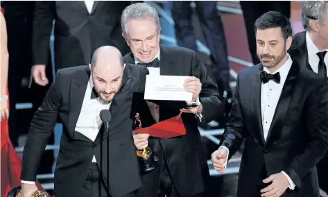  ?? CHRIS PIZZELLO/ THE ASSOCIATED PRESS ?? In this Feb. 26, 2017, file photo, Jordan Horowitz, producer of La La Land, left, shows the envelope revealing Moonlight as the true winner of best picture at the Oscars, in Los Angeles, as presenter Warren Beatty and host Jimmy Kimmel, right, look on....