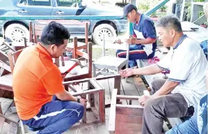  ??  ?? Gambar atas dan dibawah ANTARA ibu bapa bertungkus-lumus memperbaik­i kerusi kayu yang rosak.