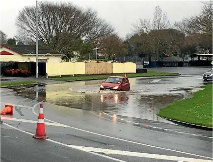  ?? PHOTO: GEORGIA FORRESTER/STUFF ?? A car negotiates surface flooding at the corner of Botanical and Park roads, Palmerston North.