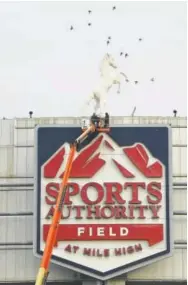  ?? RJ Sangosti, The Denver Post ?? Crews from Ad Light Group work on disconnect­ing electrical wires to signage at Sports Authority Field at Mile High on Monday.