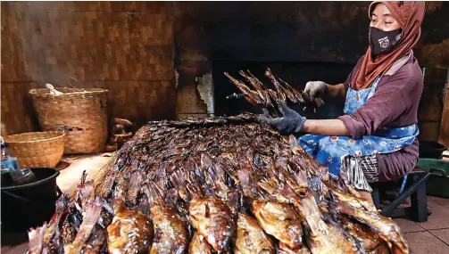  ?? DIMAS MAULANA/JAWA POS ?? KEMBALI DICARI: Seorang pekerja mengasapi ikan mujair di Desa Penatarsew­u, Tanggulang­in, kemarin. Omzet mereka sempat turun 50 persen, tetapi kini mulai naik lagi.