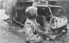  ??  ?? An Indian soldier patrolling next to a burned out vehicle after clashes with supporters of the separatist Gorkha Janmukti Morcha (GJM) group in Darjeeling. — AFP photo