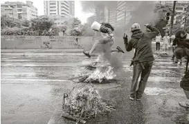  ?? Ariana Cubillos / Associated Press ?? A masked protester jumps over a burning barricade in Caracas, Venezuela, on Wednesday as authoritie­s continue their search for a helicopter pilot who on Tuesday fired at the nation’s Supreme Court and Interior Ministry.