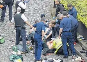  ?? STEFAN ROUSSEAU/ASSOCIATED PRESS ?? Conservati­ve lawmaker Tobias Ellwood, center, performs first aid on a wounded police officer.