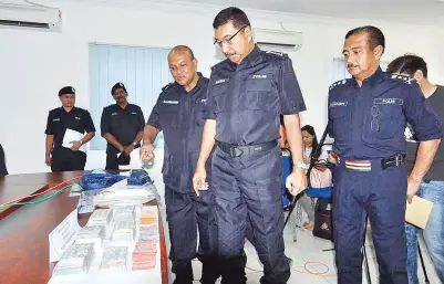  ??  ?? RAMLI (tengah) meneliti wang tunai lebih RM72 ribu yang dilarikan suspek, sambil diperhatik­an Razarudin (kanan) dan Salehuddin (kiri) selepas sidang media di IPD Penampang, kelmarin.