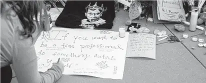  ?? JASON ANDREW/THE NEW YORK TIMES ?? A mourner writes a message on a sign placed at a memorial to Ruth Bader Ginsburg in Washington on Saturday.