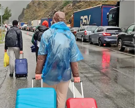  ?? ?? Escape: Pulling suitcases, Russians head for Georgia alongside traffic jams following Putin’s mobilisati­on