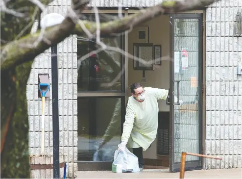  ?? Carlos Osorio / Reuters Files ?? A woman retrieves a bag left at the front door of Pinecrest Nursing Home in Bobcaygeon, Ont., on March 30
after several residents died and dozens of staff were sickened due to COVID-19.