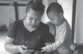  ?? YIRMIYAN ARTHUR/AP ?? Diana Khumanthem, 30, looks at photos June 28 with her nephew Hridhaan, who lost his mother, Ranjita, to COVID-19, in Imphal, Manipur, India.