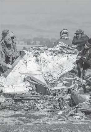  ?? MULUGETA AYENE / THE ASSOCIATED PRESS ?? Workers on Monday take car of the grim task of securing the scene of an Ethiopian Airlines flight crash near Bishoftu, or Debre Zeit.