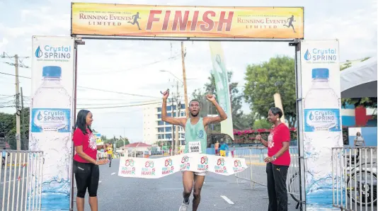  ?? GLADSTONE TAYLOR/MULTIMEDIA PHOTO EDITOR ?? Garfield Gordon (centre) crosses the finish line to win the Run For Your Heart 5K and 2K Road Race at Emancipati­on Park in New Kingston yesterday.