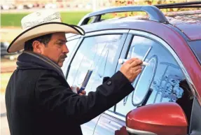  ?? TREVOR HUGHES/USA TODAY ?? Jose Vargas, 56, draws “vote” and “vota” on his Mazda SUV in Dodge City, Kan. He gave voters rides to the polls.