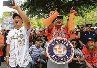  ?? Melissa Phillip / Houston Chronicle ?? Nguyen H. Le, left, and Chris Wiggin join the throng cheering on the World Series champs during the fan fest event before Monday’s home opener at Minute Maid Park.