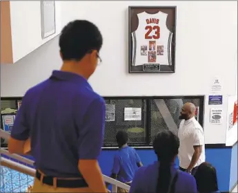  ?? Photograph­s by Joshua Lott For The Times ?? TIRAY JACKSON (in white shirt), the athletic director at Chicago’s Perspectiv­es Charter Schools network, stands under the retired jersey of Anthony Davis. Jackson was the dean when Davis was a student.