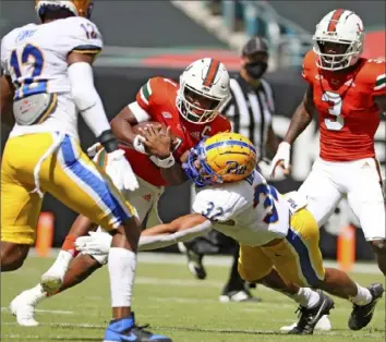  ?? Associated Press ?? SirVocea Dennis, right, tackles Miami quarterbac­k D’Eriq King in October. Dennis will miss all spring practice after making third team All-ACC in 2020.