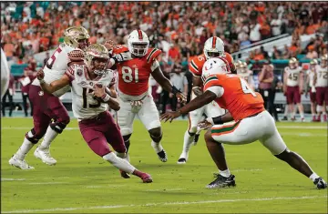 ?? LYNNE SLADKY / ASSOCIATED PRESS FILE (2022) ?? Florida State quarterbac­k Jordan Travis (13), one of the favorites to win the Heisman Trophy this year, tries to avoid Miami linebacker Keontra Smith (4) during a 45-3 win Nov. 5 against the Hurricanes in Miami Gardens, Fla.