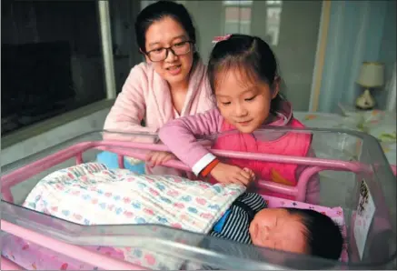  ?? LIU JUNXI / XINHUA ?? A mother and her daughter watch over the family’s newborn baby at an infant healthcare center in Hefei, Anhui province, on Dec 2.