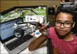  ??  ?? Bastrop Middle School student Chris Shaw holds a wheeled robotic device that was programmed to accomplish tasks during competitio­n.