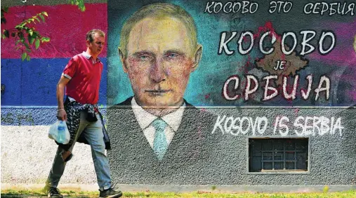  ?? EFE ?? Un hombre pasa junto a un mural de Vladimir Putin en una calle de Belgrado donde se lee «Kosovo es Serbia»