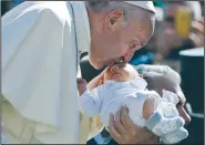  ?? AP/ANDREW MEDICHINI ?? Pope Francis kisses a baby Wednesday as he arrives for his weekly general audience at the Vatican.